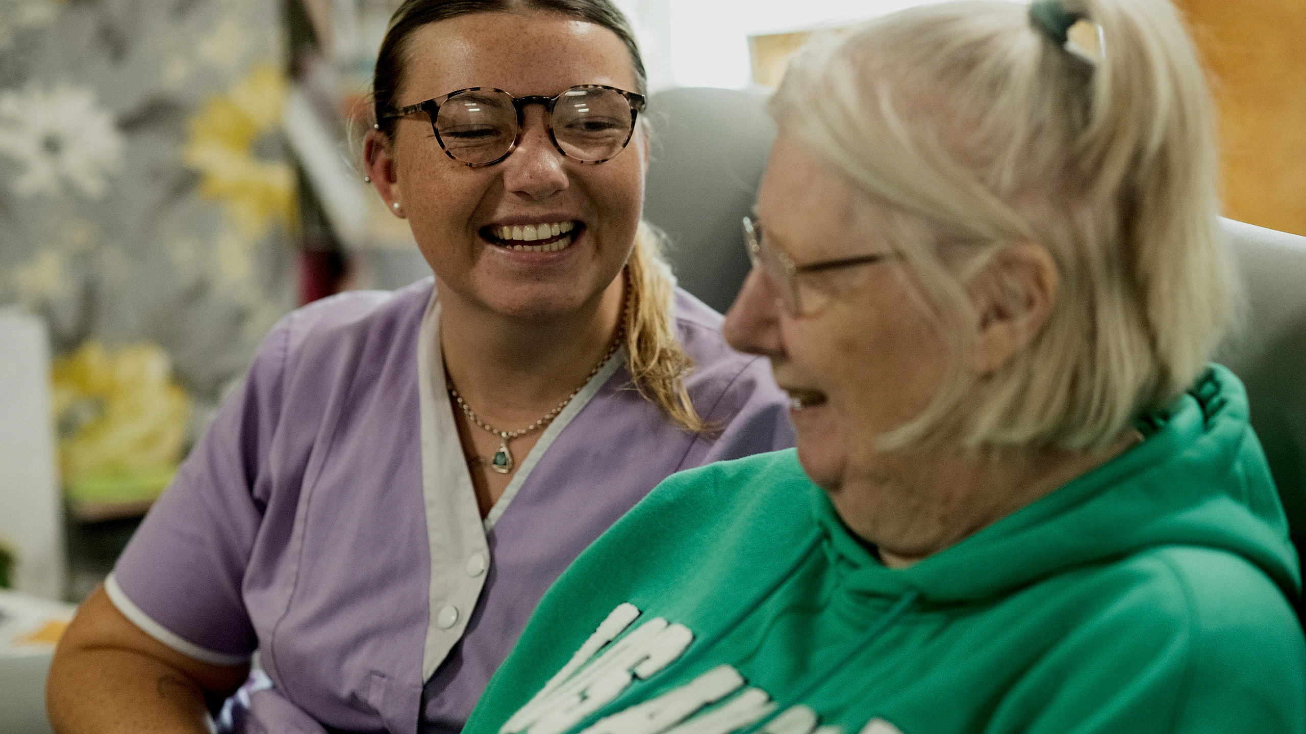 Caregiver smiling with an older adult indoors