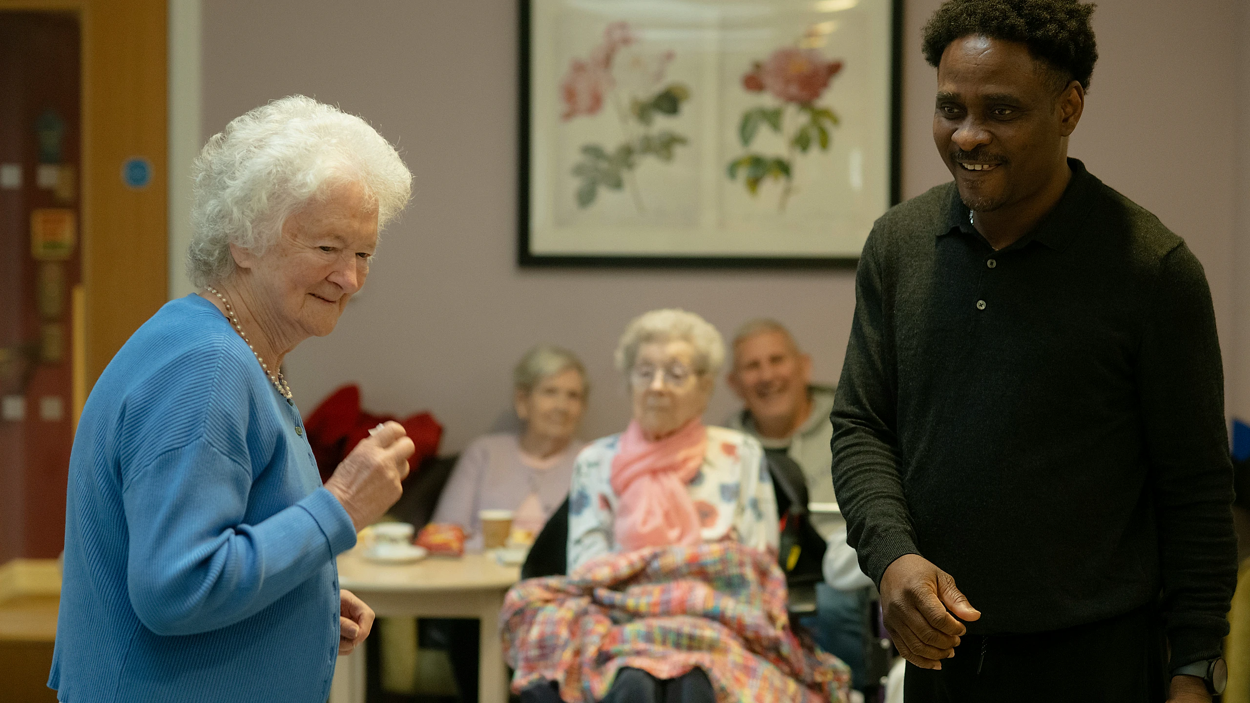 Care professional supporting older adults in a common room